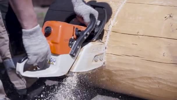 Close-up of man sawing electric saw log. Clip. Carpenter saws cleaned beam for construction with wooden structure. Convenient and fast sawing with electric saw — Stock Video