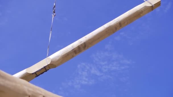 Grue soulève faisceau sur fond de ciel bleu. Clip. La grue sur le chantier soulève du bois traité lourd sur le chantier de construction — Video