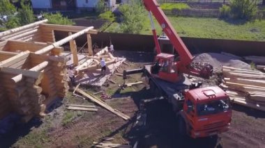 Turna ve işçiler ahşap ev inşaatında. Şarjör. Ülke ahşap evi inşa etmek için işçilerden oluşan bir ekiple çalışma sürecinin en üst görünümü