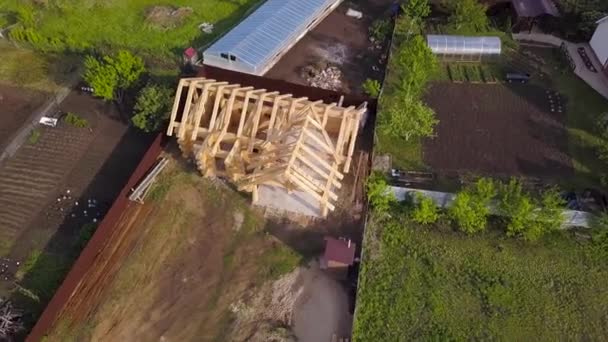 Plot with construction of wooden house. Clip. Top view on frame of wooden house on private country plot in summer. Frame of wooden house in process of construction — ストック動画