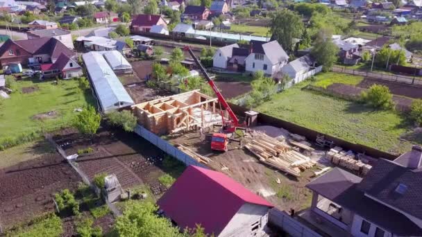 Byn med trähus under uppbyggnad. Klipp. Ovanifrån av processen för konstruktion av trähus på bakgrund av angränsande lantliga stugor — Stockvideo