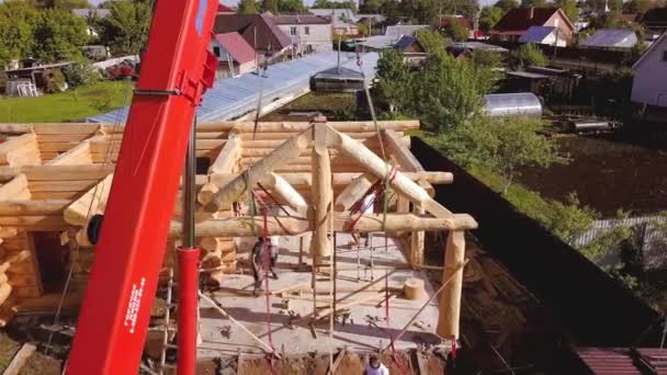 Stavební personál instaluje střechu. Klip. Horní pohled na instalaci části dřevěné střechy s jeřábem a konstrukčním týmem. Proces výstavby rámu dřevěného domu — Stock video