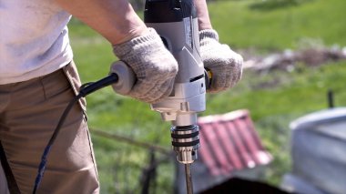 Kereste delmek için elektrikli matkaplara yakın çekim. Şarjör. Çubuklarda ya da kalın odunlarda delik açmak için büyük elektronik matkap. Spiral matkap ucu günlüğe vidalanmış