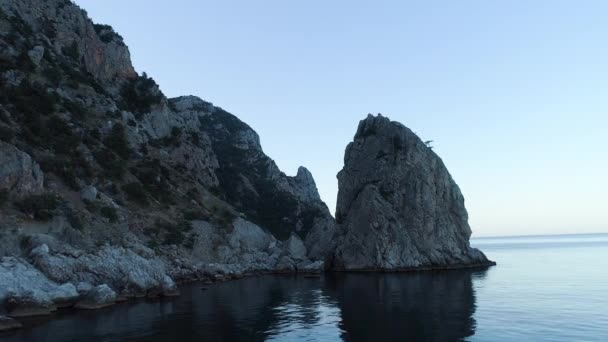 青空を背景に青い海と野生の崖のトップビュー。撃たれた空を背景に青い海の穏やかな水が地平線に達するロッキー海岸 — ストック動画