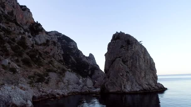 Top view of wild cliffs with blue sea on sky background. Shot. Rocky coast with calm water of blue sea reaching horizon on background of sky — Stock Video