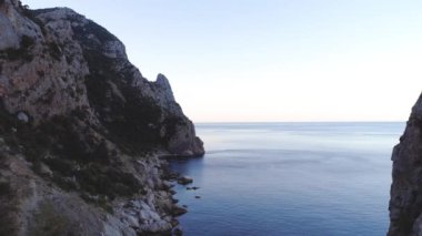 Denizdeki kayaların en üst görüntüsü. Vuruldu. Erozyon etkisi altındaki kaya, genel dağ kütlesinden ayrıldı. Sakin deniz kıyısının güçlü kaya kütleleri