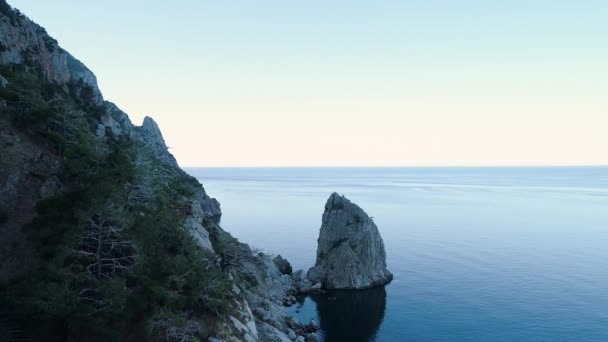 Κάτοψη του θαλασσινού τοπίου με βραχώδη ακτή. Πυροβολήθηκε. Βραχώδης ακτή με σκοτεινή πλευρά σε φόντο γαλάζιας θάλασσας και ορίζοντα με ουρανό. Θαλάσσια ακτή με βραχώδη ορεινό όγκο — Αρχείο Βίντεο