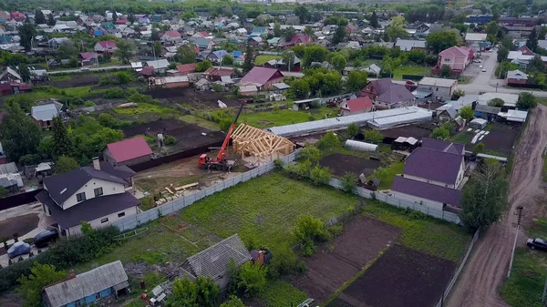 Вид сверху на загородный город с новым домом. Клип. Новый строящийся деревянный дом выделяется на фоне панорамы коттеджной деревни — стоковое фото