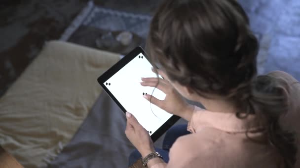 Sandalyede oturan kahverengi saçlı genç kadının üst görünümü, ipad tutarak, yazarak ve renk anahtar beyaz ekranda kayar. Stok görüntüleri. Smartphone yeni teknoloji konsepti — Stok video