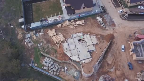 Utsikt från ovan av byggarbetsplatsen pågår, arbetare bygga nya hus eller verkstad och byggmaterial trä styrelser, stenar, tegel. Klipp. Process av nybyggnation. — Stockvideo