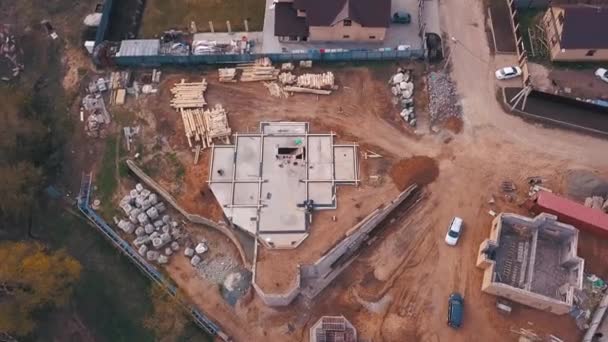 Uitzicht vanaf boven op de bouwplaats in uitvoering, arbeiders bouwen nieuwe huis of werkplaats en bouwmaterialen houten planken, rotsen, bakstenen. Clip. Proces van nieuwbouw bouw. — Stockvideo