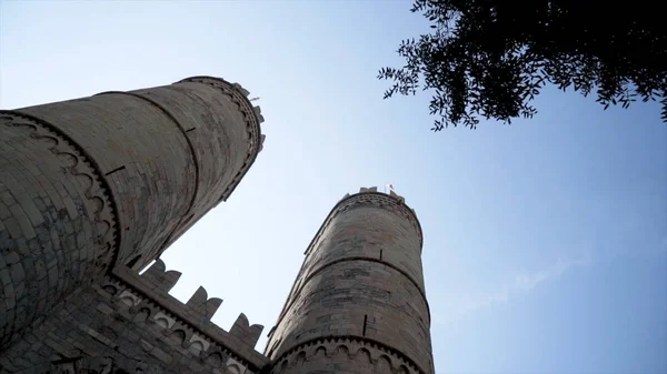 Bottom view of old fortress towers. Action. Two towers of old castle rise on background of blue sky. Beautiful and powerful view of ancient construction of fortress towers