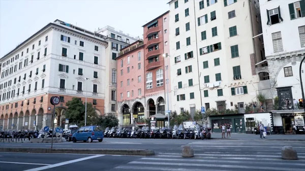 Cesta s projíždějícími auty na pozadí starého města. Akce. City Road na pozadí obytných výškových budov v evropském stylu. Parkování motocyklů na chodnících u silnice — Stock fotografie