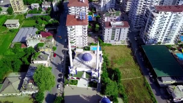 Ovanifrån av stadens moské på sommaren. Klipp. Liten gammal moské i södra staden. Muselman stad med enkel moské i sommar. Liten moské omgiven av stadens höghus — Stockvideo