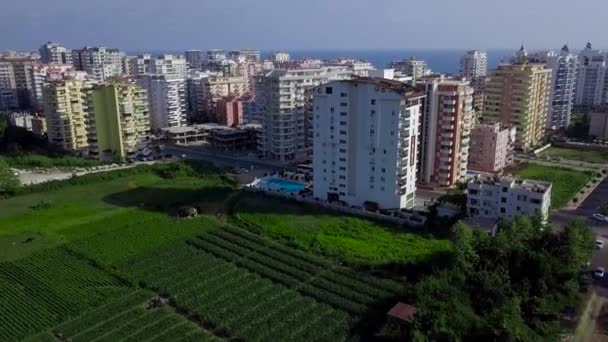 Vista superior da cidade verde resort no fundo do mar e montanhas. Clipe. Paisagem bonita com plantas verdes entre edifícios de arranha-céus de recurso de cidade na costa — Vídeo de Stock