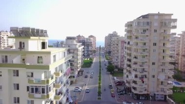 Denize çıkan şehir yolunun üst manzarası. Şarjör. Şehrin yüksek binalarının arasından geçen yol ufukta denize çıkar. Kasaba otellerinin deniz manzaralı düz yol manzarası