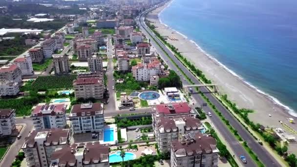 Vista superior de la ciudad turística costera. Clip. Hermosa ciudad turística con casas de varios pisos y hoteles ubicados en la costa por el agua. Paisaje de la ciudad turística está separada del mar por carretera — Vídeos de Stock