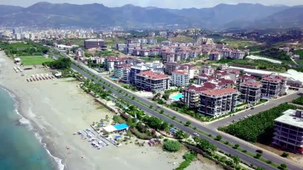 Vue de dessus de la station balnéaire côtière. Clip. Belle ville de villégiature avec des maisons à étages et des hôtels situés sur la côte par l'eau. Ville située au bord de la mer dans une zone montagneuse au climat tropical — Video