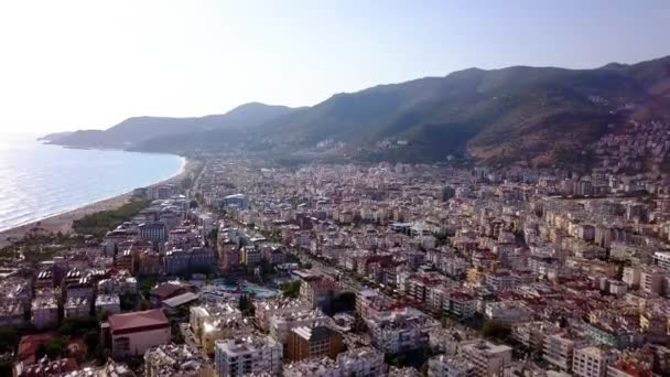 Alberghi di località costiera sullo sfondo del mare e delle montagne. Clip. Vista dall'alto del bellissimo panorama della località estiva con mare. Vacanze estive nella località costiera con clima tropicale — Video Stock