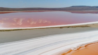 Pembe göl manzaralı güzel bir manzara. Vuruldu. Pembe suyla doğa gölünün dünya dışı mucizesi. Pembe gölü, beyaz kumu ve ufukta dağları olan güzel bir manzara.