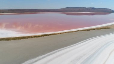 Pembe göl manzaralı güzel bir manzara. Vuruldu. Pembe suyla doğa gölünün dünya dışı mucizesi. Pembe gölü, beyaz kumu ve ufukta dağları olan güzel bir manzara.