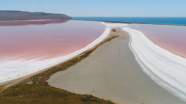 Pembe göl manzaralı güzel bir manzara. Vuruldu. Pembe suyla doğa gölünün dünya dışı mucizesi. Pembe gölü, beyaz kumu ve ufukta dağları olan güzel bir manzara.