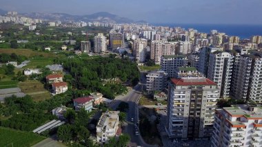 Deniz ve dağların arkasındaki yeşil şehrin en üst manzarası. Şarjör. Sahildeki yüksek binalar arasında yeşil bitkilerle güzel bir manzara.