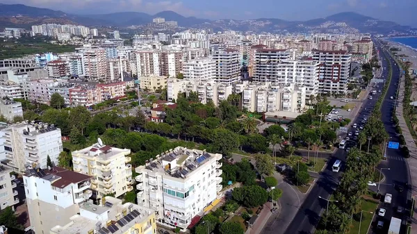 Top view of resort town on sea coast on background of mountains. Clip. Southern resort town located on coast is separated from sea by highway — Stock Photo, Image