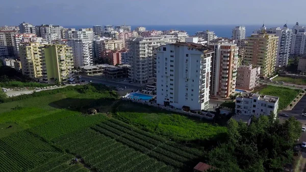 Top view of resort green city on background of sea and mountains. Clip. Beautiful landscape with green plants among resort high-rise buildings of city on coast — Stock Photo, Image