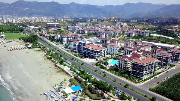 Top view of coastal resort town. Clip. Beautiful resort town with multi storey houses and hotels located on coast by water. City located by sea in mountainous area with tropical climate — Stock Photo, Image