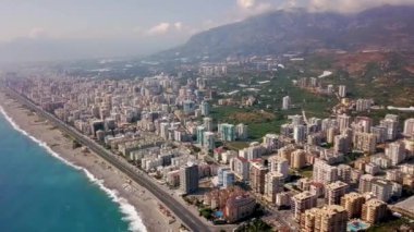 Dağların arkasındaki deniz manzaralı güzel büyük şehir manzarası. Şarjör. Mavi deniz ve dağ manzarası üzerinde yer alan güney tatil köyünün panoraması