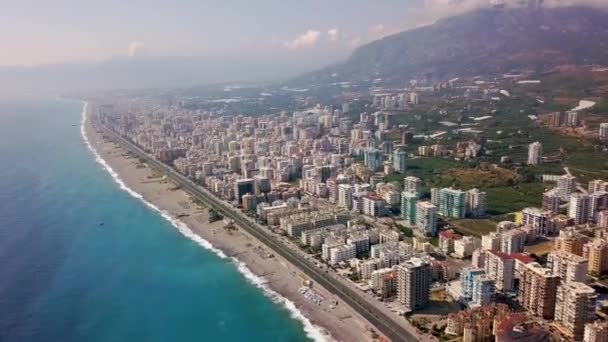 Vue de dessus de la belle grande ville par la mer sur fond de montagnes. Clip. Panorama de la station balnéaire sud située sur la côte de la mer bleue et paysage de montagne — Video