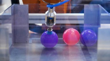 Uluslararası sergi olan cam kutudan plastik topları toplayan bir robot için kapatıyoruz. Medya. Küçük toplar alan bir makinenin geleceksel ve bilimsel arka planı.