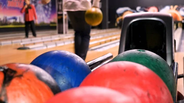 Zavřít pro muže ruku s míčem z regálu a hodit ho na bowling Lane. Média. Hráč hodí bowlingovou kouli, která srazí a kutálí. — Stock fotografie