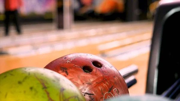 Close up pro osobu, která bere míč a házení do bowlingové dráhy, bowling skupinové hry. Média. Mnoho pestrobarevných bowlingových koulí, muž si vybral jednu z nich. — Stock fotografie