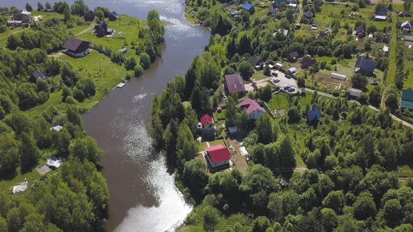 Luftaufnahme einer Stadt mit vielen grünen Bäumen entlang des Flusses an einem sonnigen Sommertag. Clip. ökologisch saubere Gegend mit kleinen, schönen Häusern und schmalem Fluss. — Stockfoto