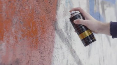 Elinde sprey boya kutusu ve duvara renkli grafiti çizmek, sokak sanatı konsepti. Başla. Duvarında sprey sprey boya olan bir ressamın yan görüntüsü, beton boya..