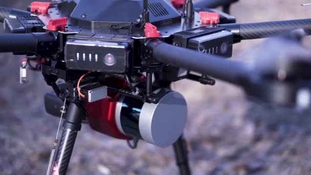 Close up for the quadcopter mechanism on blurred background. Clip. Turned on quadrotor with installed camera standing on the ground. — Stock Video