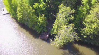 Barışçıl nehir ve orman kıyısı, insansız hava aracı tarafından vuruldu. Şarjör. Nehir, ahşap iskele ve güneşli bir yaz gününde kıyı boyunca uzanan birçok yeşil ağaçlı doğal manzara için hava..