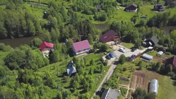 Flygfoto av färgglada hus i en by nära floden, fridfull plats för att leva. Klipp. Moderna stugor belägna i skogsområdet en solig sommardag. — Stockvideo