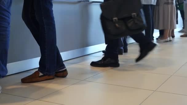 Vista de las piernas de los clientes de pie en la oficina moderna, recibiendo servicio en el banco. Medios. La gente está haciendo cola para el servicio en el departamento de un banco . — Vídeos de Stock