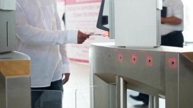 İş binasının modern elektronik girişi, teknoloji geçmişi. Medya. Beyaz gömlekli bir adam biletini tarıyor ve geçiyor..