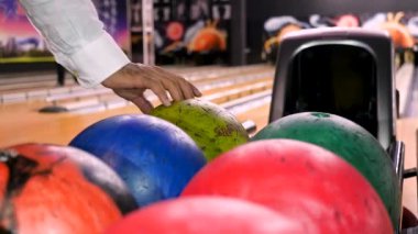 Bir bovling kulübünde bowling oynarken topu atmadan önce topu tutan adam için yakın çekim. Medya. Spor ve eğlence konsepti, raftan top alan adam..