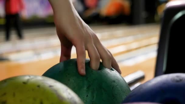 Gros plan pour une personne prenant une balle sur fond de bowling ruelles, jeu de groupe de bowling. Les médias. Beaucoup de boules de bowling de couleur variée, l'homme choisissant l'un d'eux . — Video