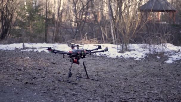 Närbild för svart Drone stående på marken innan flygningen, antenn video och Foto skytte koncept. Klipp. Quadcopter börjar rotera sina blad och ta av. — Stockvideo