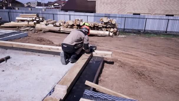 Bakre bild av snickare i uniform under arbetsprocessen, byggande av ett trähus. Klipp. Att göra grunden för framtidens trähus, som arbetar utanför. — Stockvideo