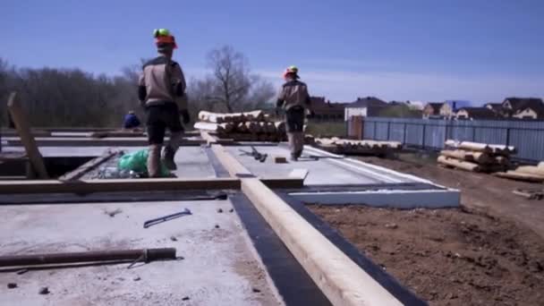 Zadní pohled na Tesary v uniformě během pracovního procesu, stavba dřevěného domu. Klip. Tvorba základů budoucího dřevěného domu, práce venku. — Stock video