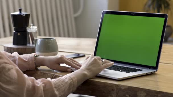 Close-up voor vrouw handen met een gouden ring op de vinger met behulp van haar laptop met groen scherm staande op tafel in modern appartement. Stock footage. Thuis werk, laptop met Chromakey. — Stockvideo