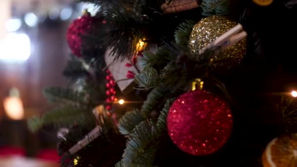 Neujahrsbälle und Girlanden auf verschwommenem Hintergrund, Urlaubskonzept. Rahmen. Weihnachtskomposition aus Tannenzweig, goldenen und roten Weihnachtskugeln, roten Beeren.