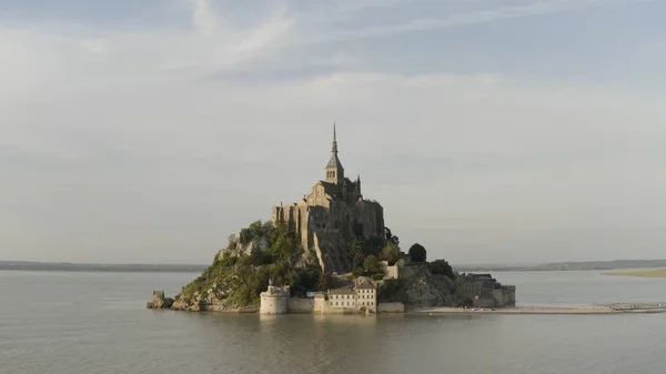 Letecký panoramatický výhled na jedinečný chrám na ostrově obklopený mořem na modrém oblačném pozadí oblohy. Akce. Úžasný hrad Mont-Saint-Michel, Francie. — Stock fotografie